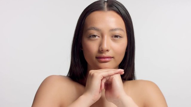 mixed race asian model in studio beauty shoot Tilt movement of camera model with head rest on hands watching straight to the camera