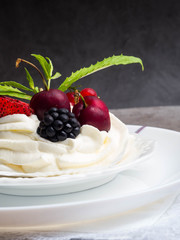 Meringue dessert Pavlova cake with fresh berries, mint on a stone background