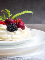 Meringue dessert Pavlova cake with fresh berries, mint on a stone background