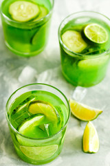 Homemade trendy iced matcha green tea or lemonade with cucumber and lime in a glass on light gray background top view.Healthy cold vegan beverage for hot summer day.Super food drink