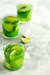 Homemade trendy iced matcha green tea or lemonade with cucumber and lime in a glass on light gray background.Healthy cold vegan beverage for hot summer day.Super food drink.Vertical orientation