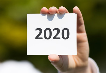 Woman hand showing white card with 2020 text