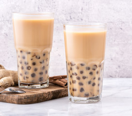 Popular Taiwan drink - Bubble milk tea with tapioca pearl ball in drinking glass on marble white table wooden tray background, close up, copy space