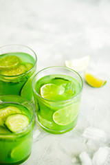 Fototapeta premium Homemade trendy iced matcha green tea or lemonade with cucumber and lime in a glass on light gray background top view.Healthy cold vegan beverage for hot summer day.Super food drink