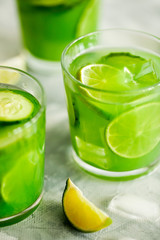 Homemade trendy iced matcha green tea or lemonade with cucumber and lime in a glass on light gray background close-up.Healthy cold vegan beverage for hot summer day.Super food drink