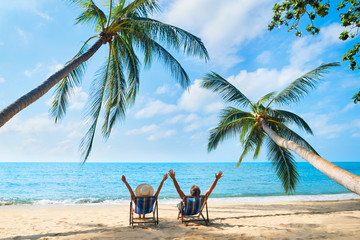 Happy couple with arms up relax on the beach enjoy beautiful sea on the tropical island