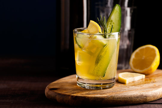Fresh organic summer cocktail made with sour ginger craft beer or kombucha tea with cucumber and lemon on wooden background.Drink on the bar table with copy space.Trendy vegan refreshing beverage