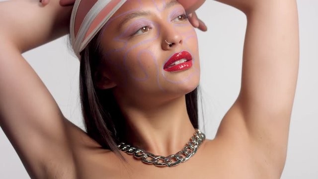 mixed race asian model in studio creative art makeup with hands up poses to a camera
