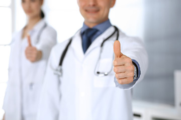 Group of doctors showing thumbs up. Perfect medical service in clinic. Happy future in medicine and healthcare concept