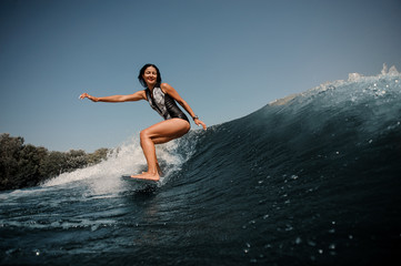 Naklejka na ściany i meble Brunette woman surfing on the surfboard in sea