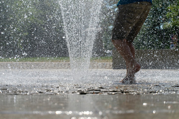 Barefoot person running through a fountain