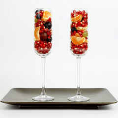 two glasses with fruits on brown plate on white background