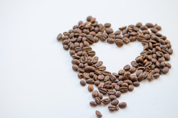 Ein Haufen geröstete Kaffeebohnen mit einem Loch in Herzform auf weißem Hintergrund lädt zum Kaffeegenuss ein