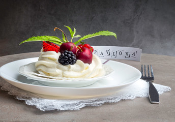 Piece of meringue cake Pavlova with whipped cream and fresh strawberry, blackberry, cherry, currant, mint