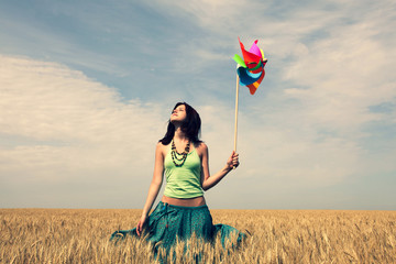 Girl with wind pinwheel at wheat field