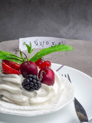Piece of meringue cake Pavlova with whipped cream and fresh strawberry, blackberry, cherry, currant, mint