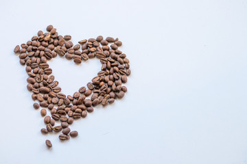 Ein Haufen geröstete Kaffeebohnen mit einem Loch in Herzform auf weißem Hintergrund lädt zum Kaffeegenuss ein