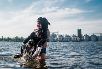 Man plays with a pet - a giant schnauzer dog	