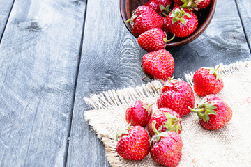 ripe red strawberries scattered on a table on burlap.