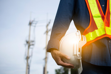 Engineering holds white safety hats and electric pole background