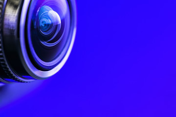 Camera lens and dark blue backlight. Side view of the lens of camera on blue background. Camera...