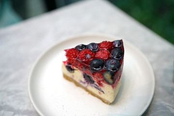 Homemade mixed berries jelly cheesecake on marble table and blurred background.