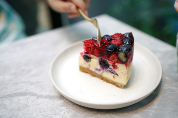 Homemade mixed berries jelly cheesecake on marble table and blurred background.