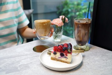 Set of Hot coffee latte, Iced mocha and Homemade mixed berries jelly cheesecake on marble table and blurred background.