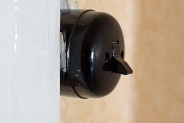 Old black round light switch close up.