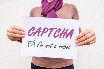 hands holds paper sheet width words CAPTCHA i'm not a robot