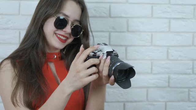 Young photographer. A cute girl in sunglasses looks at a photo in a camera.