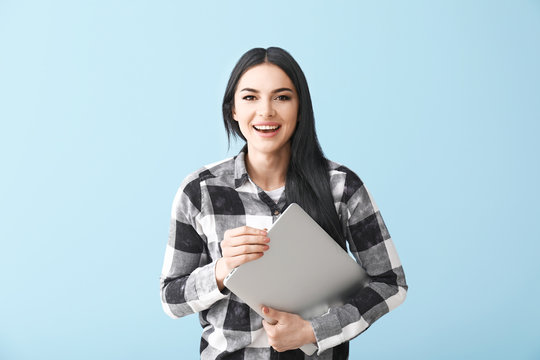 Happy female programmer with laptop on color background