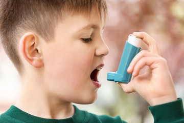 Boy with inhaler having asthma attack on spring day