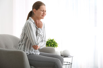 Young woman suffering from pain in elbow at home