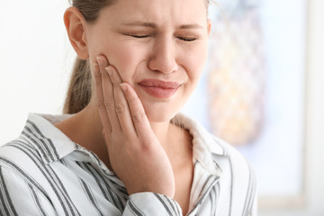 Young woman suffering from toothache at home
