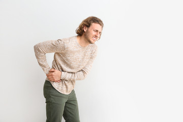 Young man suffering from back pain on white background