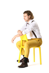 Stylish young man sitting on chair against white background