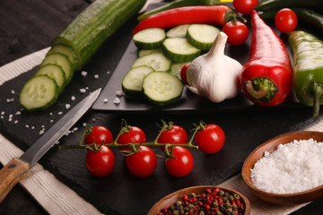 Healthy food. Vegetables on a black plate and stone cutting board and wooden background.