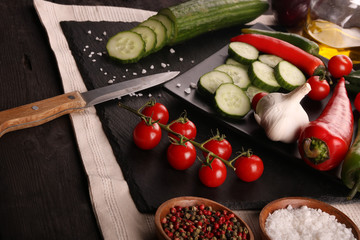 Healthy food. Vegetables on a black plate and stone cutting board and wooden background.