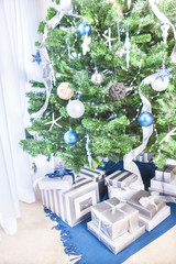 Green tree with christmas decoration and gift boxes.
