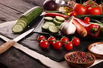 Healthy food. Vegetables on a black plate and stone cutting board and wooden background.