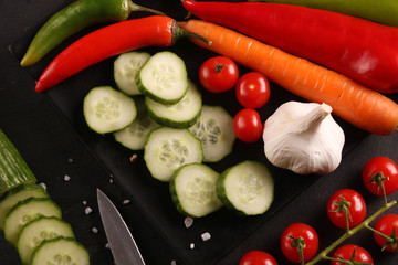 Healthy food. Vegetables on a black plate and stone cutting board and wooden background.