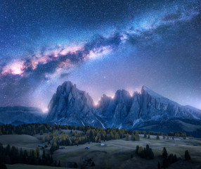 Colorful Milky Way over beautiful mauntains at night.  Autumn landscape with mountains, sky with stars and bright milky way, buildings, trees, high rocks. Alpe di Siusi in Dolomites, Italy. Space © den-belitsky