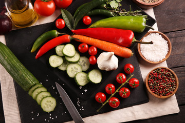 Healthy food. Vegetables on a black plate and stone cutting board and wooden background.