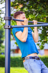 Obraz premium Workout in summer: Young fit Caucasian man is doing pull ups