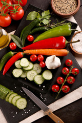 Healthy food. Vegetables on a black plate and stone cutting board and wooden background.