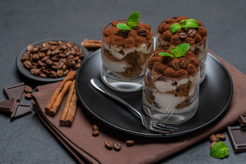 Classic tiramisu dessert in a glass on dark concrete background
