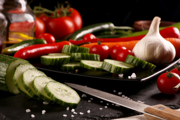 Healthy food. Vegetables on a black plate and stone cutting board and wooden background.