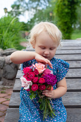 cute blonde girl is holding a bouquet of flowers