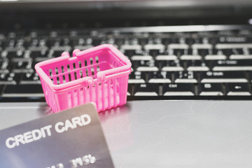 Basket shopping and hand holding mock up of credit card on laptop keyboard. Consumer can buy products directly anywhere anytime from seller using web browser. Online shopping and e-commerce concept.